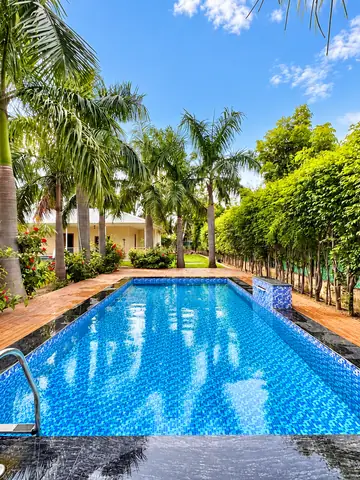View across the swimming pool towards the farmhouse at Mulberry Farm, Noida